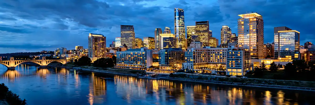 Downtown Minneapolis skyline and Mississippi riverfront hotels at blue hour with modern glass towers and river reflections